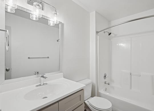 A white bathroom with a toilet, sink, and bathtub.