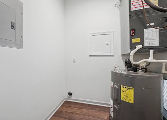 A utility room with a furnace and a white electrical box on the wall.