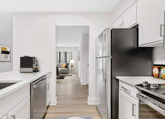 A modern kitchen with a black refrigerator and white cabinets. at Woodlyn on the Green Apartment Homes, Cary, North Carolina