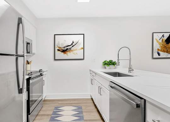 A modern kitchen with a white fridge, a sink, and a dishwasher. at Woodlyn on the Green Apartment Homes, Cary, NC