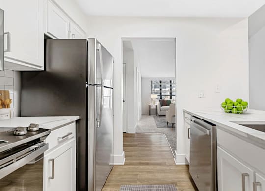 A kitchen with a black refrigerator and white cabinets. at Woodlyn on the Green Apartment Homes, Cary, NC