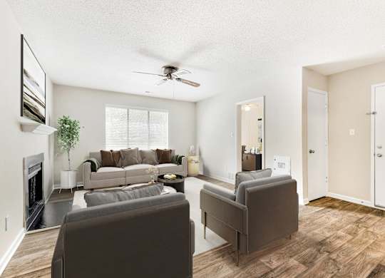 A living room with a grey couch and a fireplace. at Woodlyn on the Green Apartment Homes, Cary, 27513
