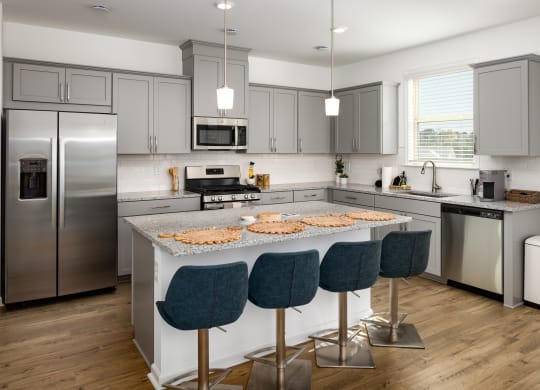a kitchen with stainless steel appliances and an island with blue chairs