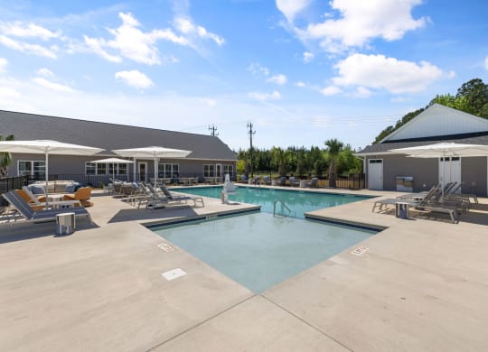 a swimming pool with chairs and umbrellas next to a building