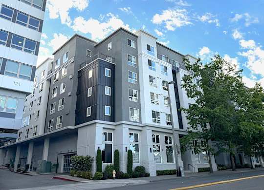 A modern multi-story building with a mix of white and dark grey balconies.