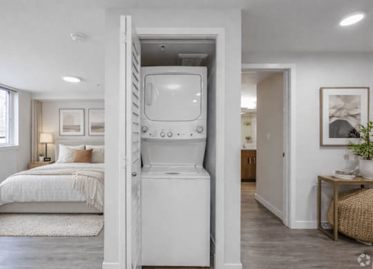 A white washing machine is built into a wall in a modern bedroom.