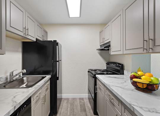View into Kitchen with Updated Flooring, Grey Cabinets, and Marble-Look Countertops at Campo Basso Apartment Homes, Lynnwood