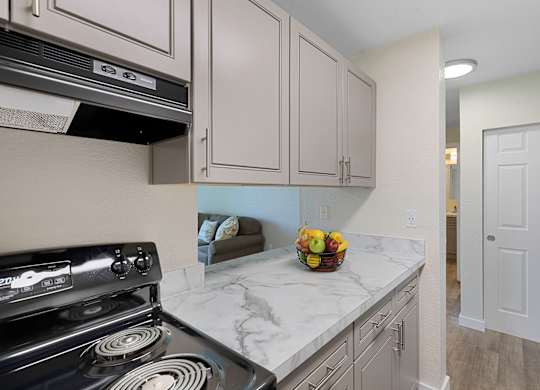 a kitchen with white cabinets and a black stove top oven at Campo Basso Apartment Homes, Washington