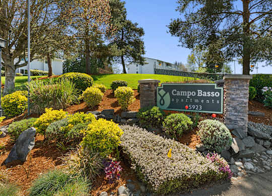 Campo Basso Property Sign with Lush Plants, Shrubs, and Bushes Under at Campo Basso Apartment Homes, Lynnwood, Washington 98087