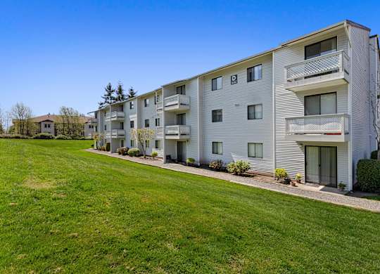 Property View of Apartment Building with Grassy Backyard Area and Wide Open Natural Space at Campo Basso Apartment Homes, Washington