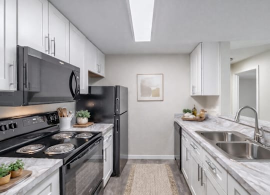 A modern kitchen with black appliances and white cabinets.