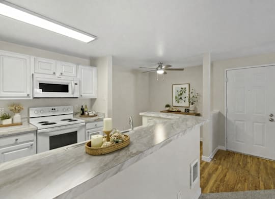 A kitchen with white cabinets and a marble countertop.