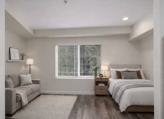 A bedroom with a bed, nightstand, and couch.