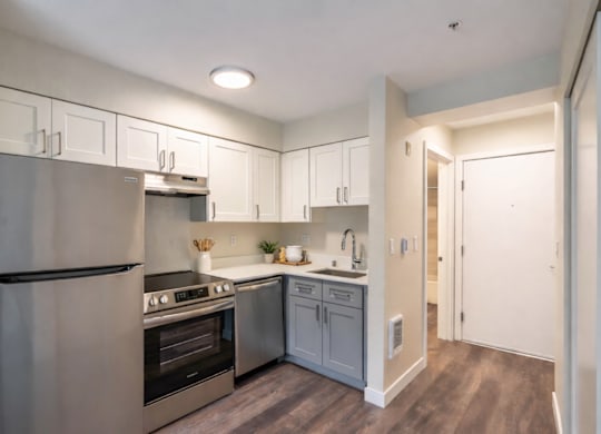 A modern kitchen with stainless steel appliances and wooden floors.