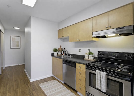 A kitchen with a black stove top oven and wooden cabinets.