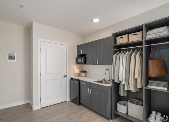 A laundry room with a sink, cabinets, and a door.