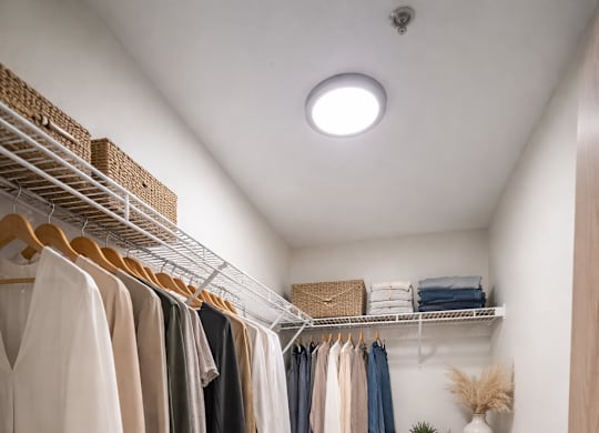 A white closet with clothes and shoes.
