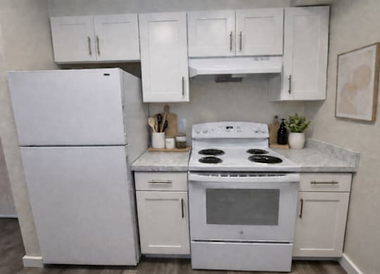 A white kitchen with a fridge, stove, and cabinets.