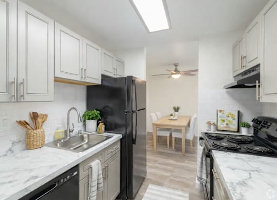 A kitchen with black appliances and white cabinets.