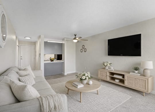 A living room with a grey couch, a wooden coffee table, and a flat screen TV mounted on the wall.