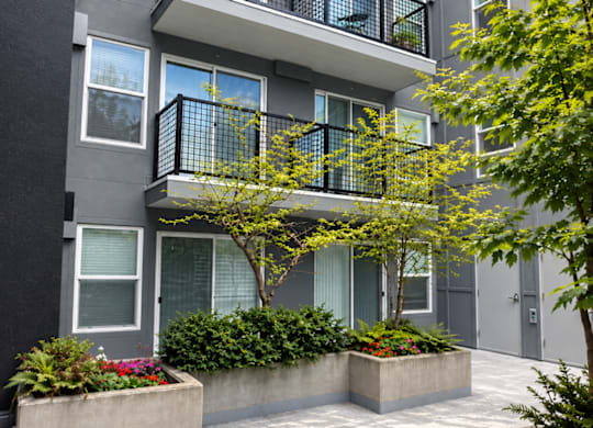 A modern apartment building with balconies and potted plants.