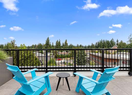 a pair of blue Adirondack chairs in the rooftop lounge area overlooking the view with a table and stool at Arabella Apartment Homes, WA 98155