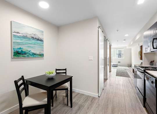 a dining area with a table and chairs and a kitchen in the background at Arabella Apartment Homes, Shoreline, WA