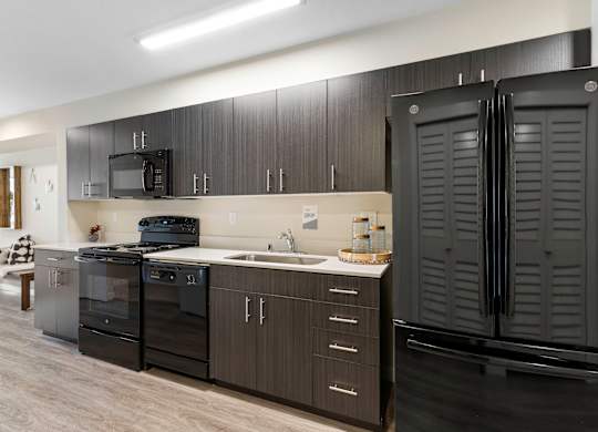 a kitchen with black cabinets and a black refrigerator at Arabella Apartment Homes, Shoreline, 98155