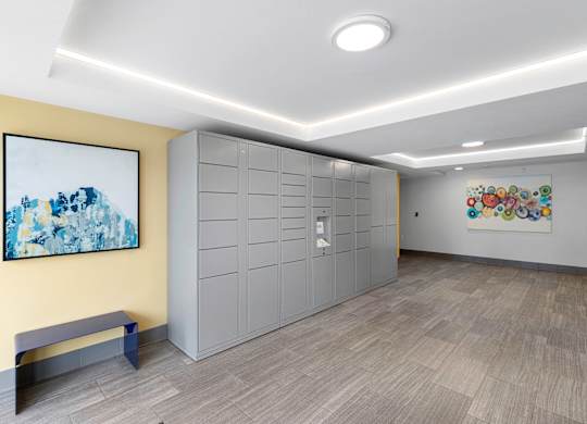 a row of package lockers with a painting on the yellow accent wall at Arabella Apartment Homes, Shoreline, 98155