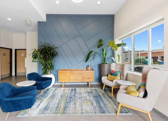 Cozy Lobby Seating Area with blue chairs and a yellow table in front of a textured blue accent wall at Arabella Apartment Homes, WA 98155