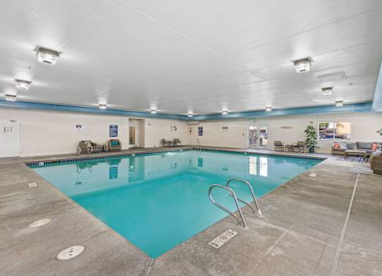 a swimming pool with chairs and tables around it  at Camelot Apartment Homes, Everett, WA, 98204