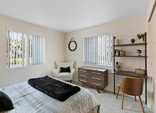 a bedroom with a bed and a desk with a chair and a dresser  at Camelot Apartment Homes, Everett, WA