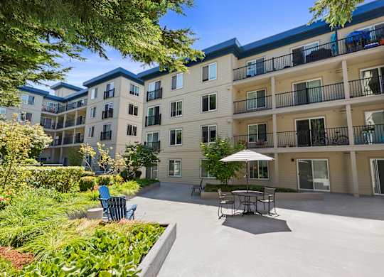 a patio with a table and chairs in front of the property building at Guinevere Apartment Homes, WA 98103