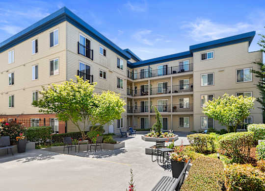 beautiful courtyard with paved area lined with plants and bushes at Guinevere Apartment Homes, Seattle, WA