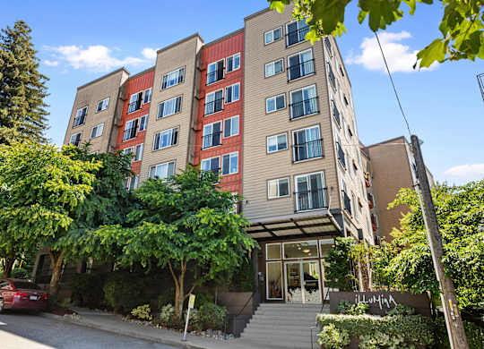 Front view of property building with an awning and trees for shade at Illumina Apartment Homes, Seattle, WA