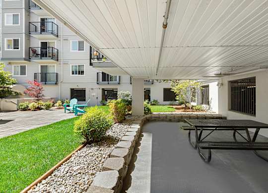 a covered patio with a picnic table and chairs at King Arthurs Court, Seattle