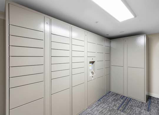 White Package Receiving Lockers in a room with a gray carpet at West Mall Place Apartment Homes, Everett