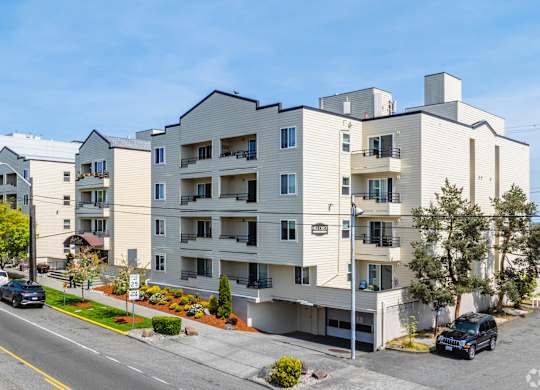 A modern apartment building with cars parked in front. at Hill Crest Apartment Homes, Seattle