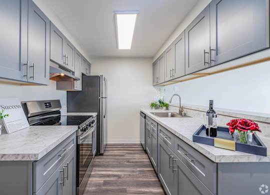 A kitchen with grey cabinets and a white countertop. at Hill Crest Apartment Homes, Seattle, 98126