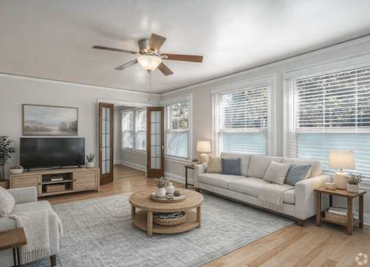 A living room with a television, a couch, a coffee table, and a ceiling fan.