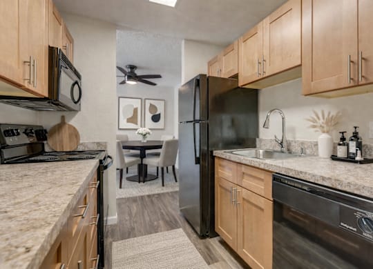 A kitchen with a black refrigerator and wooden cabinets.