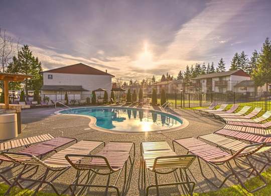 Glistening Swimming Pool at Sunset with lounge chairs and Meticulous Landscaping at Pinewood Square Apartment Homes, Lynnwood, WA