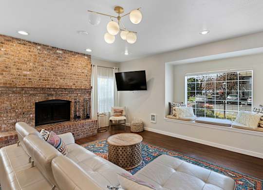 Spacious Living Room with a stone fireplace and river rock mantle with a large window at Serra Vista Apartment Homes, Lynnwood, 98087