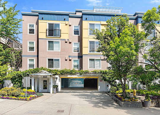 an apartment building with a driveway and trees in front of it at Sir Gallahad Apartment Homes, Bellevue, WA