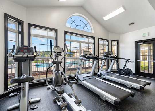 A gym with treadmills, elliptical machines, and stationary bikes. at Village on the Lake Apartments, Spring Lake, NC, 28390