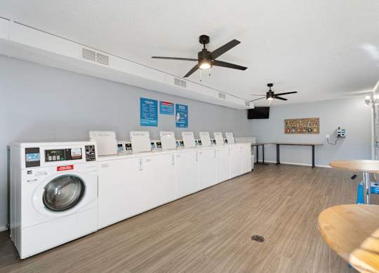 A laundromat with a row of washers and dryers at Lakes Edge Apartments, Greensboro, 27409