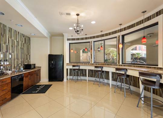 A kitchen with a black fridge and a bar area with stools at The Villagio Apartments, Fayetteville, North Carolina