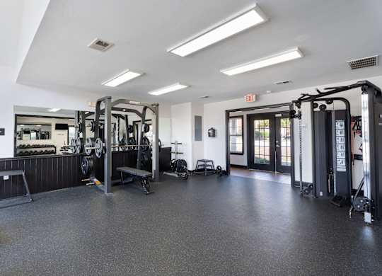 A gym with a variety of equipment including treadmills, weights, and exercise machines. at Village on the Lake Apartments, North Carolina