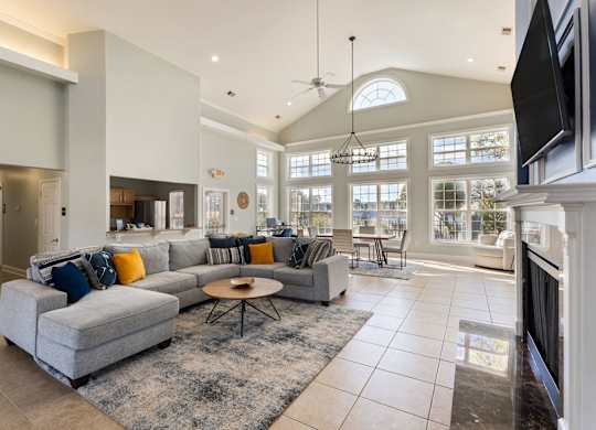 A modern living room with a grey sofa and a black television at Village on the Lake Apartments, Spring Lake