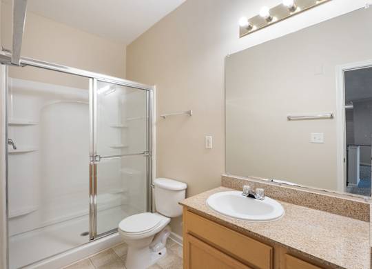 A bathroom with a toilet, sink, and shower. at Village on the Lake Apartments, Spring Lake, 28390